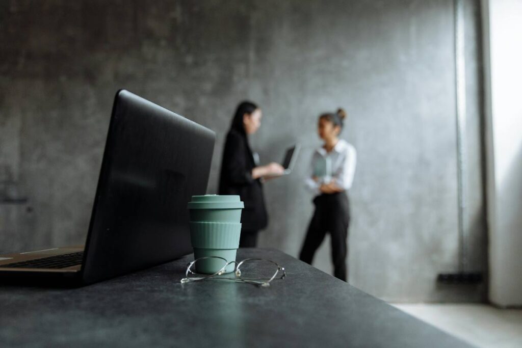Un laptop in primo piano e due ragazze sullo sfondo - prestiti.com