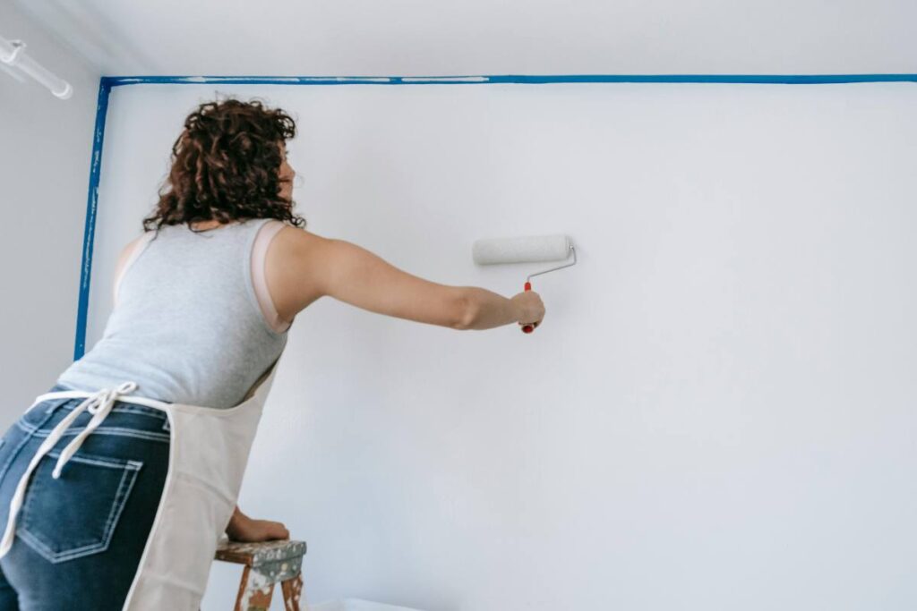 Una ragazza che dipinge una parete in casa - prestiti.com