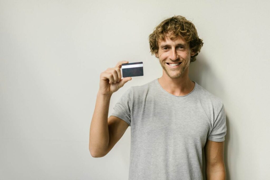 Un ragazzo mostra una carta di credito - prestiti.com