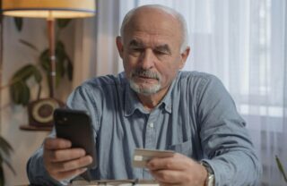Un anziano con telefono e carta di credito