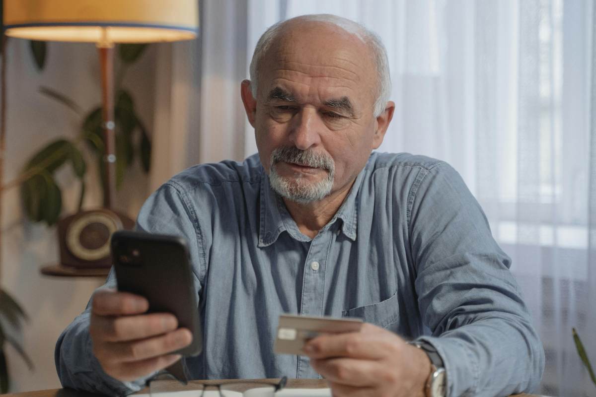 Un anziano con telefono e carta di credito