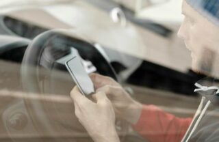 Uomo in auto che guarda il telefono