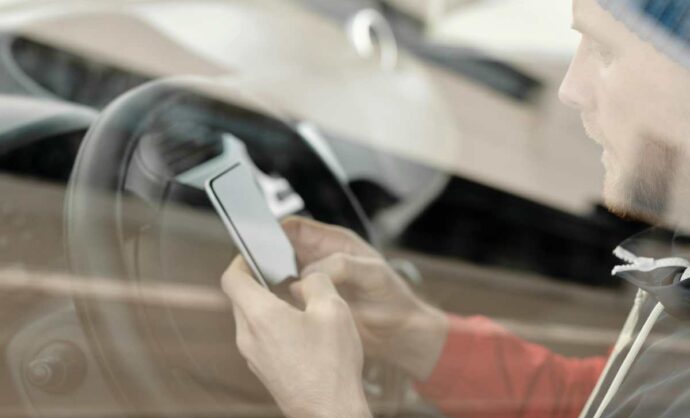 Uomo in auto che guarda il telefono