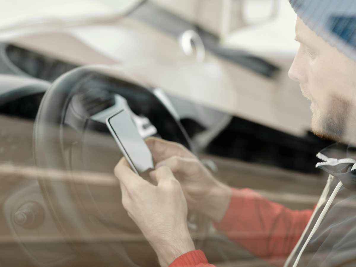 Uomo in auto che guarda il telefono