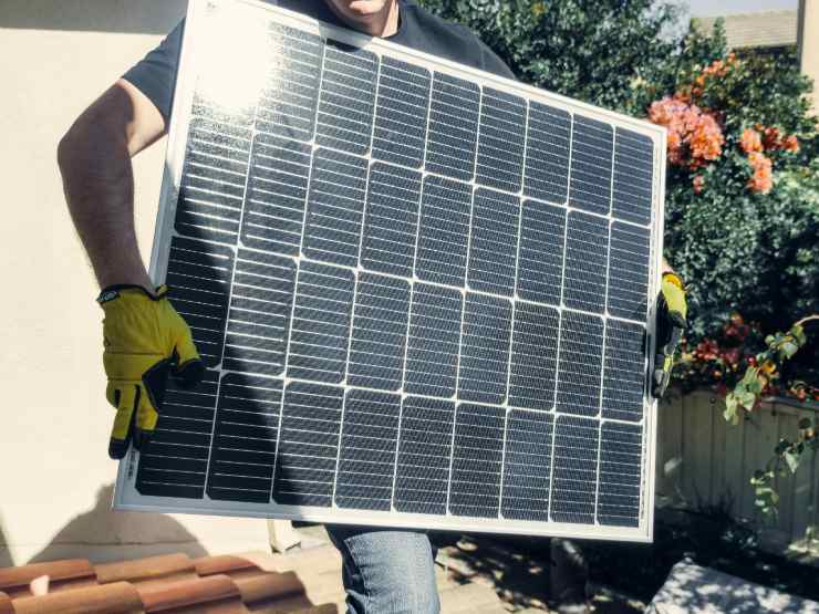 Un uomo che regge un pannello fotovoltaico - prestiti.com